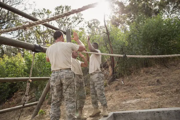 Photo of Young military soldiers giving after rope climbing during obstacle course