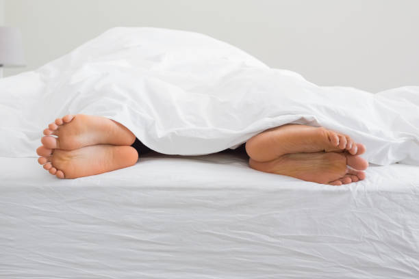 istock Couples feet sticking out from under duvet 809842768