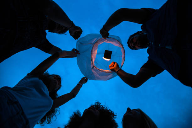 istock Friends lighting up a paper lantern at party 809852806