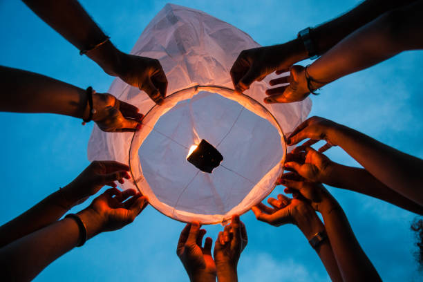 Friends lighting up a paper lantern at party