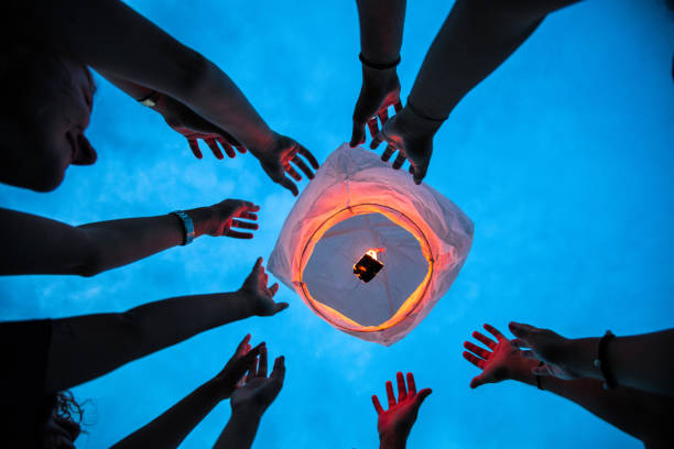 Friends lighting up a paper lantern at party