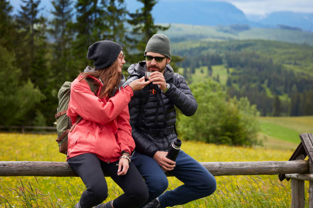 istock Couple sitting on the fence. Drinking hot tea. Mountainous landscape 809857230