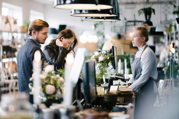 Café Scene with Customers at Till There is a small Café in a well lit, yet romantic, environment inside an old warehouse. Two people run this place on enthusiasm and their best wishes to make people's day happier via a simple but great experience. Every client is being treated like a guest in their home. scandinavian ethnicity stock pictures, royalty-free photos & images