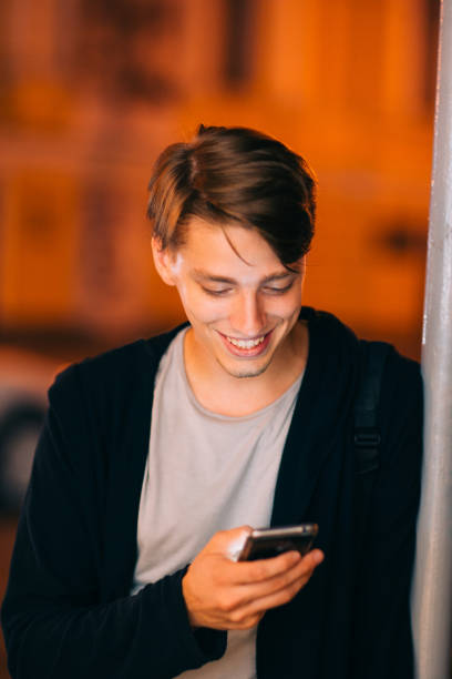 istock Smiling guy with smartphone in night city 809877754