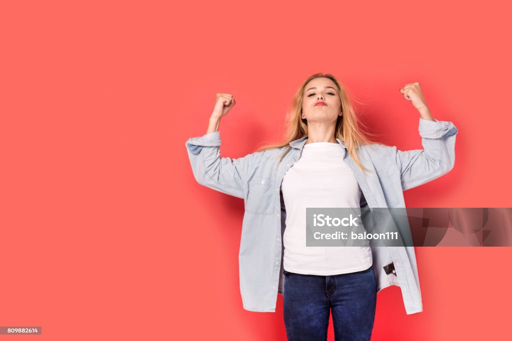 Junges blondes Mädchen zeigt ihre Stärke auf rotem Grund - Lizenzfrei Bestimmtheit Stock-Foto