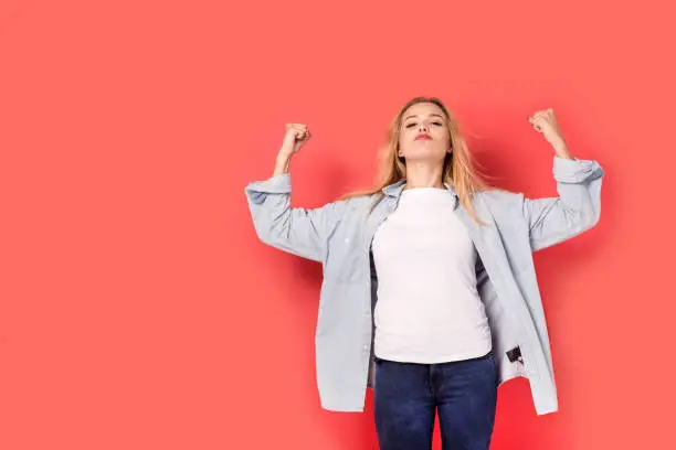 Photo of Young blonde girl shows her strength on red background