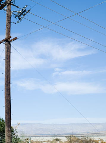 A low angle shot of an electric pole with power lines in a blue sky