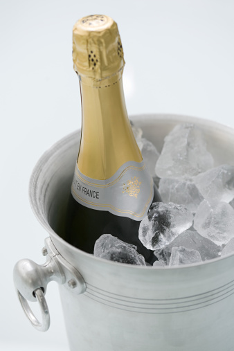 Bottle of champagne in iron ice box and two empty glasses in a luxury hotel room blurred background