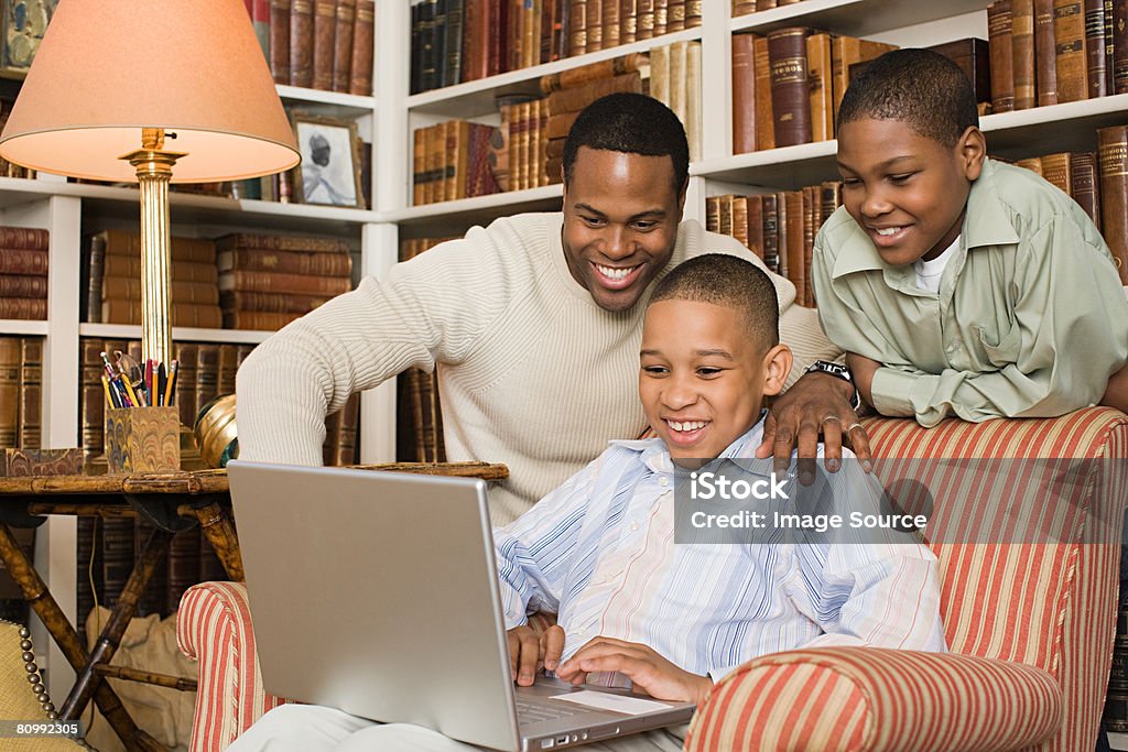 Отец с сыновьями глядя на ноутбук - Стоковые фото 30-39 лет роялти-фри
