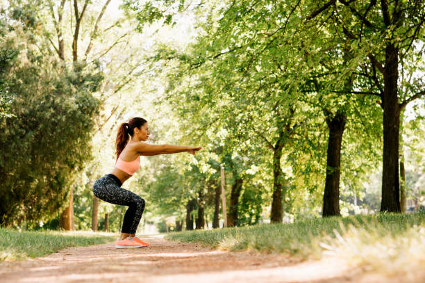 istock Beautiful caucasian girl practicing sport doing squat working out in the park 809940576