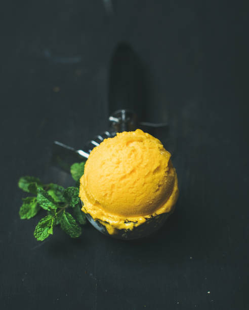 istock Mango sorbet ice cream scoop in scooper over black background 809943770