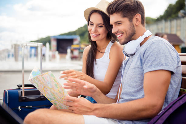 istock Young smiling tourists reading map to find way to hotel 809943792