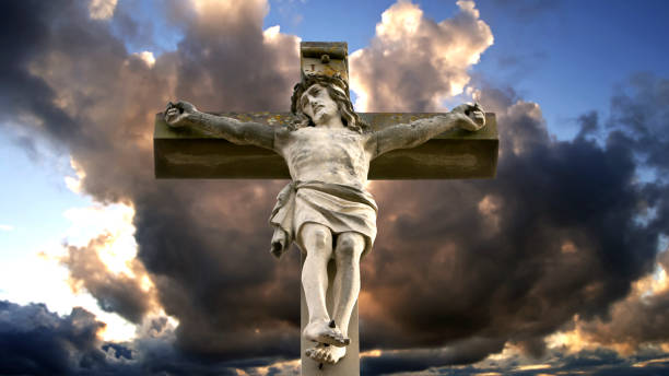 istock stone cross with Jesus and cloudy sky 809944230