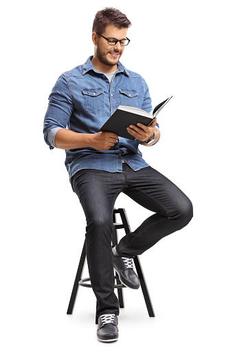 Guy sitting on a chair and reading a book isolated on white background