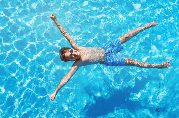 istock Happy boy floating in the swimming pool 809983416