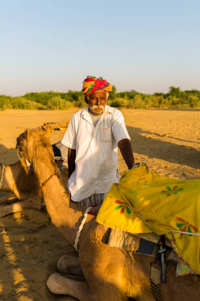 istock Rajasthani senior man in Jaisalmer Desert with a Camel, India 810002646