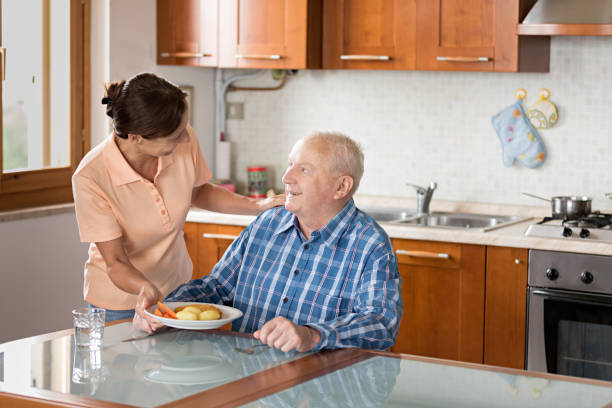 istock Home Caregiver giving senior man lunch 810005474