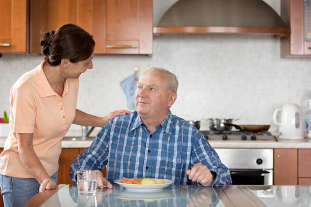 istock Home Caregiver giving senior man lunch 810005694