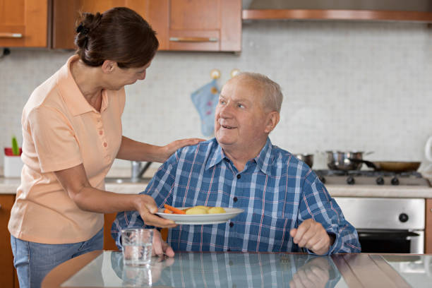 istock Home Caregiver giving senior man lunch 810005754