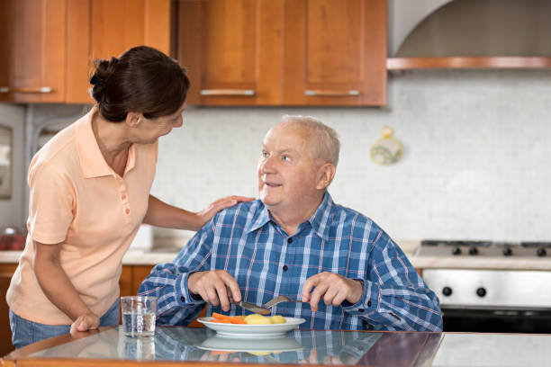 istock Home Caregiver giving senior man lunch 810006008