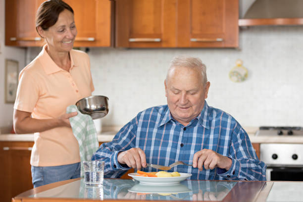 年配の男性ランチを与える介護 - senior adult nursing home eating home interior ストックフォトと画像