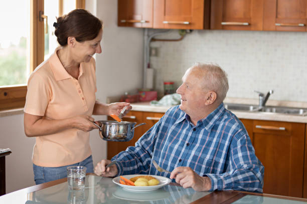 istock Home Caregiver giving senior man lunch 810011048