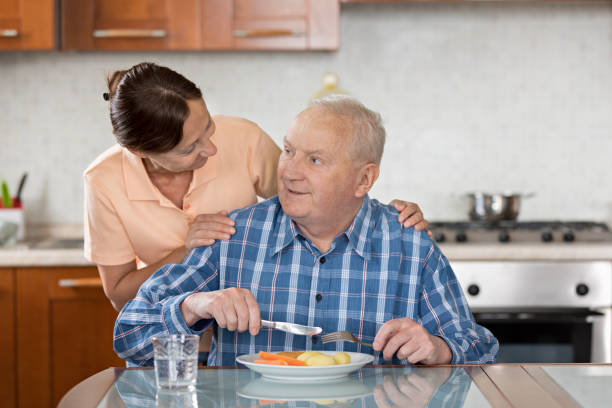istock Home Caregiver giving senior man lunch 810011214