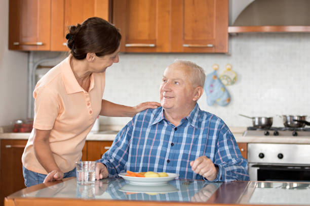 istock Home Caregiver giving senior man lunch 810011236