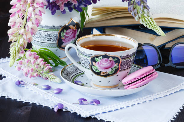 istock Romantic background with cup of tea flowers and open book over white table 810011698
