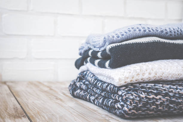 istock Stack of colored cozy knitted sweaters on a wooden rustic table, knitting bamboo needles. Toned retro. 810018768
