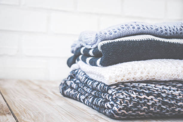 istock Stack of colored cozy knitted sweaters on a wooden rustic table, knitting bamboo needles. Toned retro. 810018878