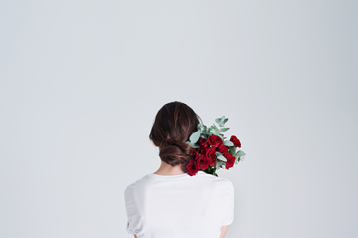 Studio shot of an unrecognizable woman holding flowers against a grey background