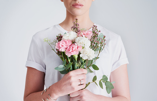 Studio shot of an unrecognizable woman holding a bunch of flowers against a grey background