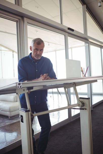 istock Mature businessman standing by workbench in office 810057696