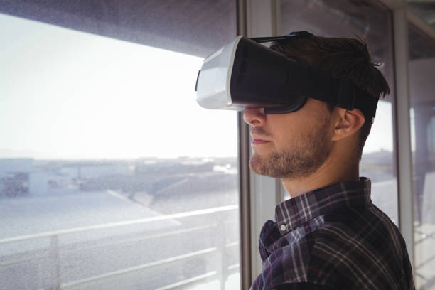istock Young businessman wearing vr headset by window in office 810059838