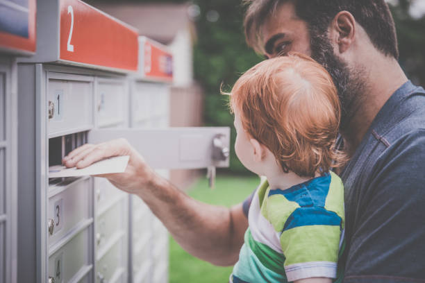 istock Baby Boy Opening a Mailbox with Parent 810062018