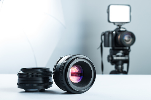 Two lenses on a white table against the background of the camera to light and softbox.