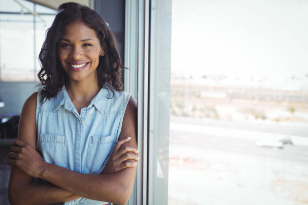 istock Smiling businesswoman standing by window in office 810070316
