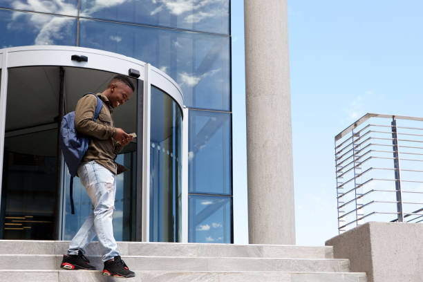 istock male student walking on campus with mobile phone 810099794