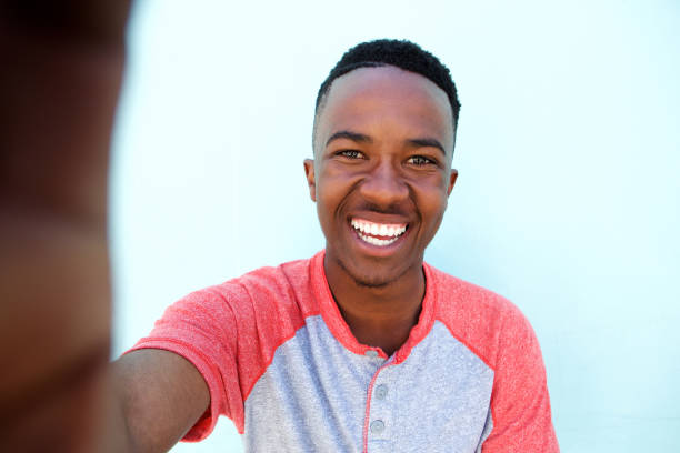 young african man smiling and taking selfie stock photo
