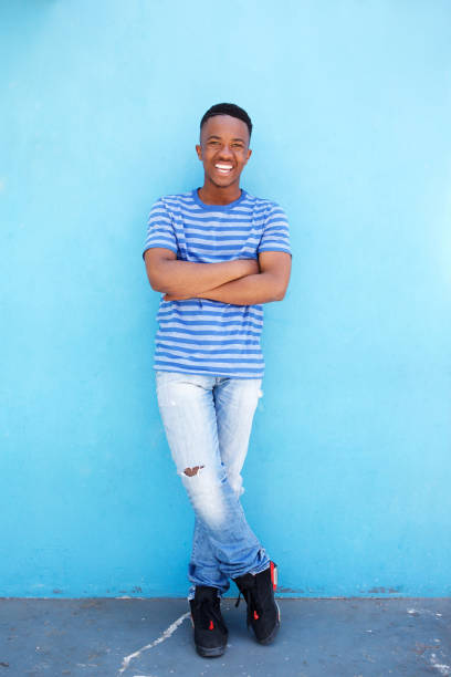 istock Full body smiling young african man leaning against blue background 810099874