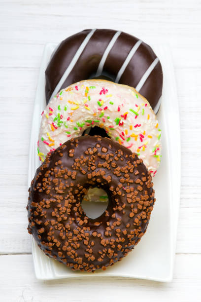 istock Tasty donuts with icing and chocolate on white wooden background, copy space 810100202