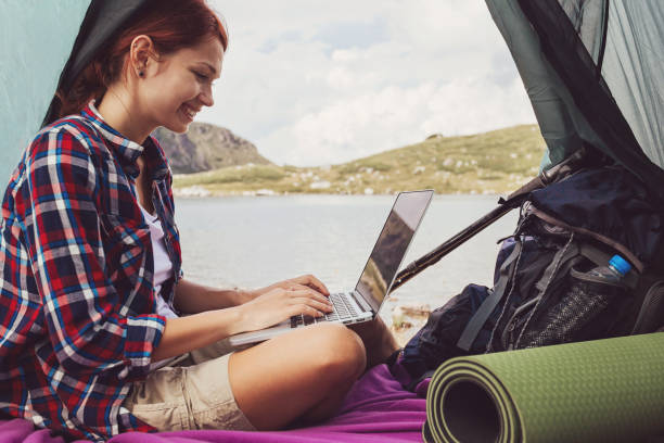 Woman using laptop inside tent in the mountain