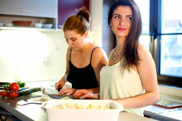 istock Two beautiful young woman prepairing dinner in the kitchen 810124790