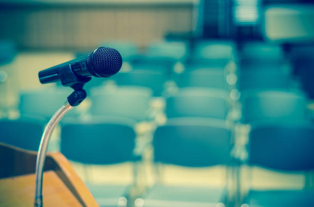 microphone sur le podium de discours sur la photo floue abstraite de fond sur le conférence hall ou séminaire la salle - new housing audio photos et images de collection
