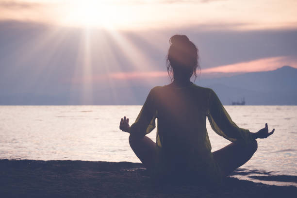 istock Female meditating on beach at sunset 810130502