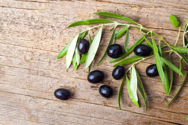 istock Dark olives on a wooden table 810150696