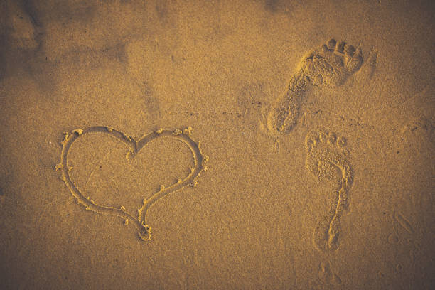 One footprint  in the Sand with sea waves crashing the shore and sunlight.