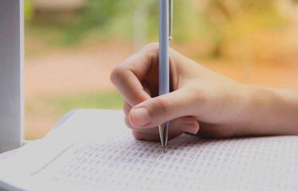 istock Woman sitting and holding a blue pencil and doing an exam 810162078