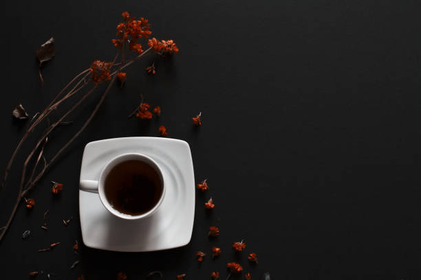 Closeup of cup of tea on dark grey background with flowers.